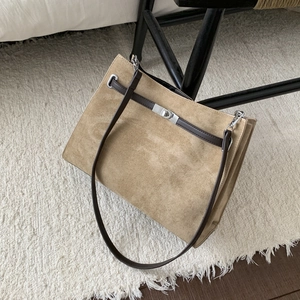 Detail of khaki suede tote bag featuring brown leather handles and silver metal turn-lock