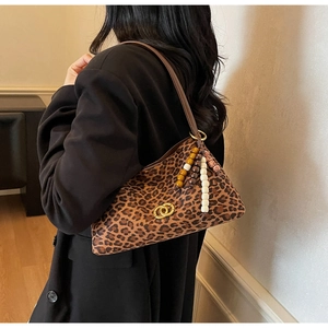 Detail showing leopard print fabric and golden buckle on a vintage underarm bag