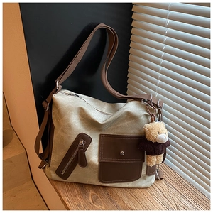 Detail of canvas tote bag with front pockets and a cute brown teddy bear keychain charm