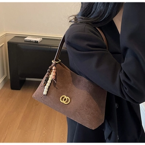 Detail view of brown matte leather shoulder bag with gold buckles and beaded charm