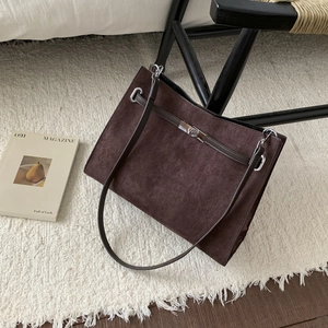 Close-up of brown suede tote bag featuring slim straps and a silver metal twist lock clasp