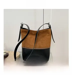 Detail view of a vintage bucket bag featuring brown suede and black leather patchwork