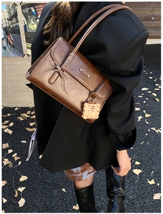 Détail d'un sac à bandoulière en cuir PU marron avec nœud et breloque biscuit