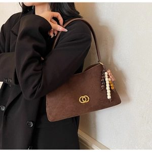 Detail of retro dark brown suede underarm bag with gold buckle and beaded charm detail