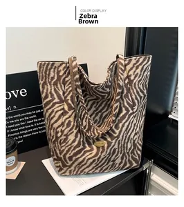 Close-up of zebra print canvas tote bag with golden metal logo and plush texture detail