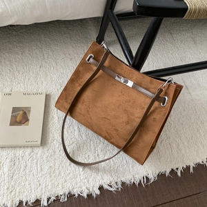 Detail of a large brown matte leather tote bag with silver twist-lock on a plush rug