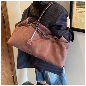 Macro detail of the large brown suede tote bag featuring adjustable leather straps and buckles
