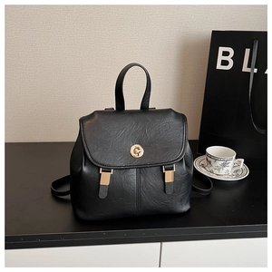 Close-up of black pebbled leather backpack with golden twist lock and flap design