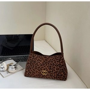 Detail of leopard print faux fur shoulder bag with gold metal buckle on white table