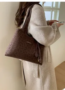 Détail du sac cabas imprimé léopard avec logo métallique et pompon décoratif