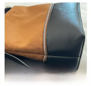 Close-up of brown suede and black leather stitching with silver zipper detail
