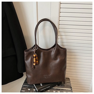 Détail du grand sac cabas en cuir marron foncé avec pompon en perles de bois et logo