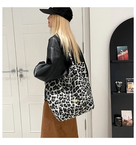 Detail of the leopard print faux fur texture and gold logo plaque on a large tote bag