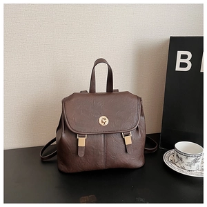 Detail of vintage brown leather backpack featuring a golden round metal buckle and top handle