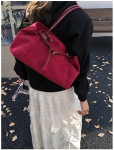 Detail view of large red suede tote bag showing soft texture and shoulder straps