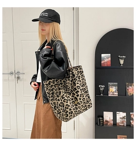 Detail of leopard print canvas tote bag with brown leather straps and metal logo tag