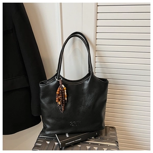 Détail d'un cabas vintage en cuir noir avec breloque en perles de bois et logo embossé