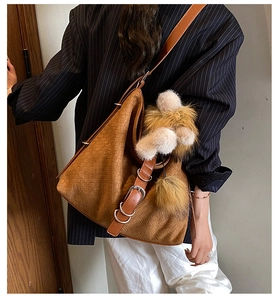 Detailed view of brown woven tote bag with adjustable strap and plush charms