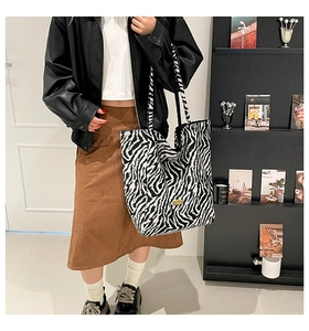 Detailed view of zebra print canvas tote bag with golden metal logo and thick fabric texture