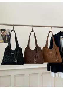Vue détaillée de grands sacs cabas léopard en noir et marron avec breloques à pompons
