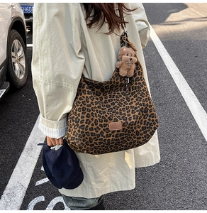 Detail view of large leopard print tote bag with plush bear charm and leather logo patch