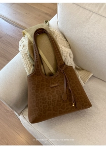Vue détaillée du sac cabas marron foncé avec texture léopard subtile et pompon décoratif