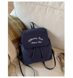 Sac à dos bleu marine avec broderie blanche présenté sur un canapé élégant