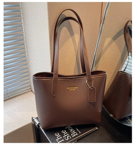 Detailed close-up of dark brown lychee pattern leather tote bag with gold logo text