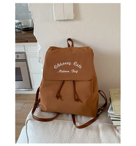 Détail du sac à dos marron caramel avec broderie blanche et fermeture à cordon en cuir