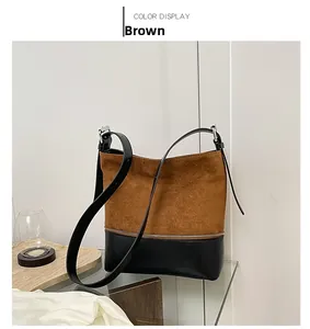 Detail view of the brown suede and black leather stitching with silver zipper on the tote bag