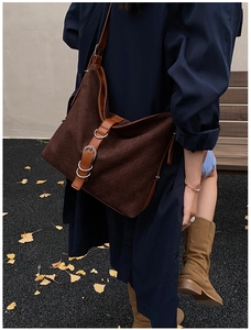 Detailed view of deep brown woven hobo bag with silver buckle on a navy trench coat
