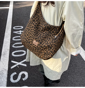 Detail of retro leopard print tote bag featuring a leather logo patch and drawstring