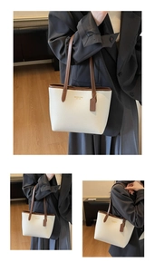 Detail of a large cream tote bag featuring brown straps and litchi texture for women