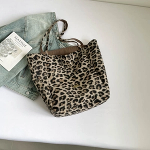 Detail of leopard print tote bag with soft texture and golden metal logo plate