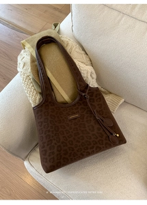Détail d'un grand sac cabas imprimé léopard marron posé sur un canapé blanc