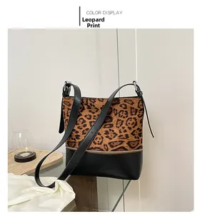 Detail view of leopard print suede and black matte leather bucket bag with silver zipper