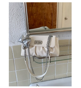 Detail of off-white pleated bag featuring a silver bow charm and sparkling diamond buckle