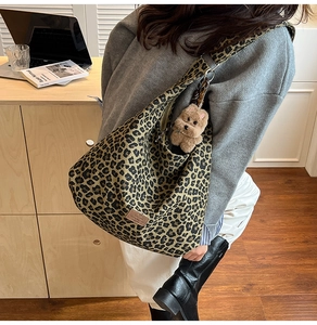 Spacious leopard print canvas hobo bag with wide strap and plush dog charm detail