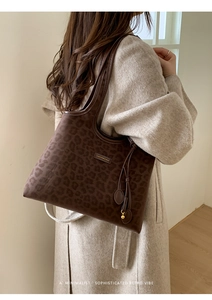 Détail du sac cabas léopard avec logo métallique et pendentif à franges élégant
