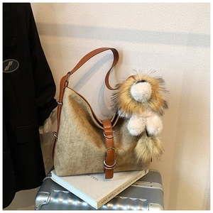 Close-up of khaki woven tote bag with brown leather straps and lion plush pendant