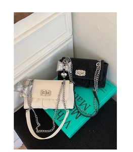 Detail of elegant chain bags with metallic bow charm and silver heart pendant