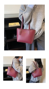 Detail view of burgundy tote bag with pebble leather texture and gold logo lettering