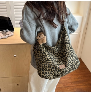 Detailed macro view of large leopard print canvas tote bag with brown plush bear charm