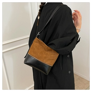 Detail view of two-tone shoulder bag showing contrast between brown suede and black leather
