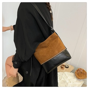 Detail of two-tone brown suede and black leather shoulder bag with adjustable strap