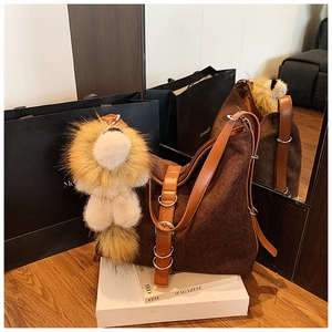 Detail of brown woven tote bag with plush lion charm and adjustable silver metal buckle