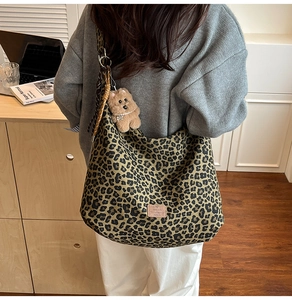 Detail of leopard print tote bag with plush bear charm and polka dot scarf on handle