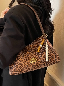 Chic leopard print underarm bag with golden interlocking buckle and colorful beaded tassel