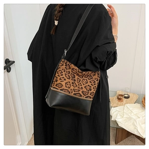 Detail view of stylish leopard print and black leather patchwork crossbody bag on shoulder