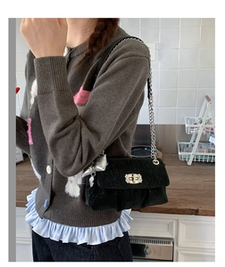 Detail of black velvet crossbody bag with silver bow charm and metal twist lock